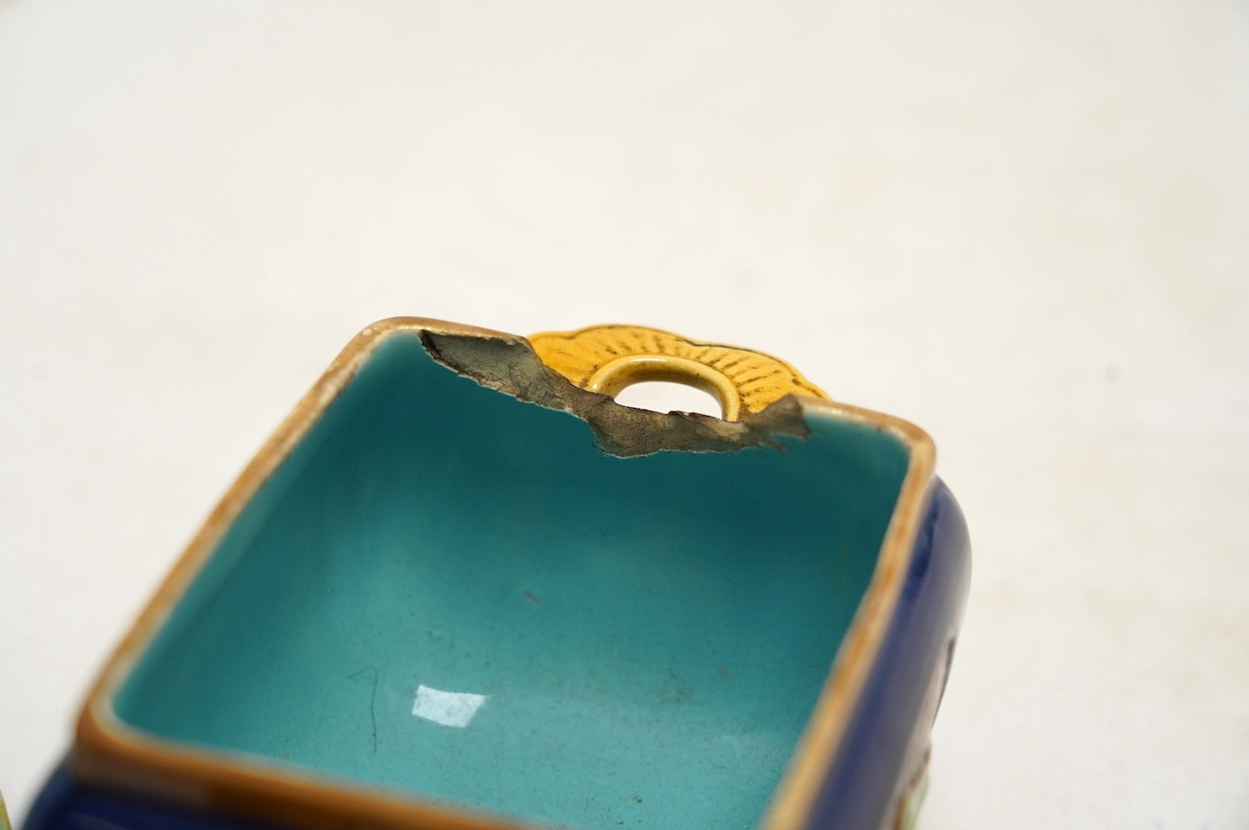 A small Minton majolica box and cover, possibly after a design by Christopher Dresser, 13cm wide. Condition - poor